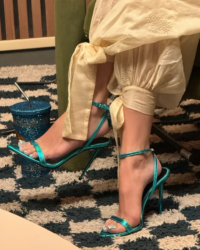 Bella Thorne wearing green heels beneath pale trousers.