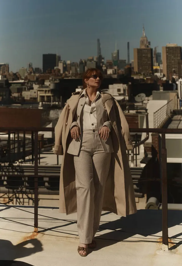 Bryce Dallas Howard standing on a rooftop terrace in a grey outfit.