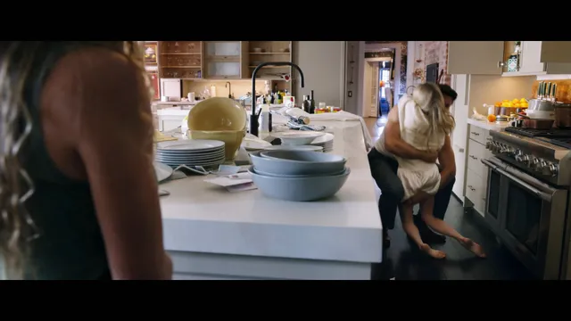 Amanda Seyfried relaxing barefoot beside a kitchen counter in a screen scene.