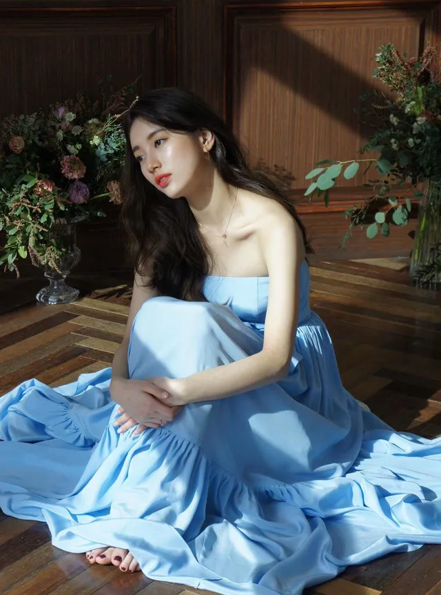 Bae Suzy sitting barefoot in a blue gown.