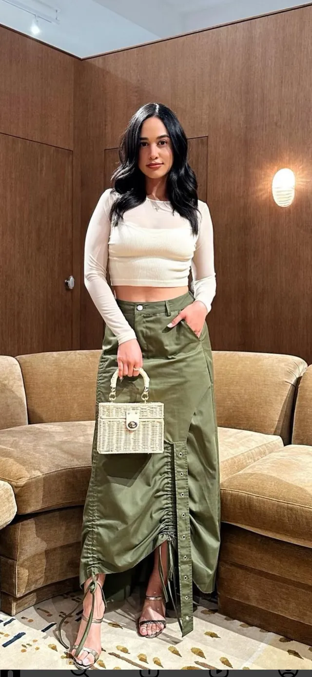 Emily Tosta wearing a green skirt and pale heels.