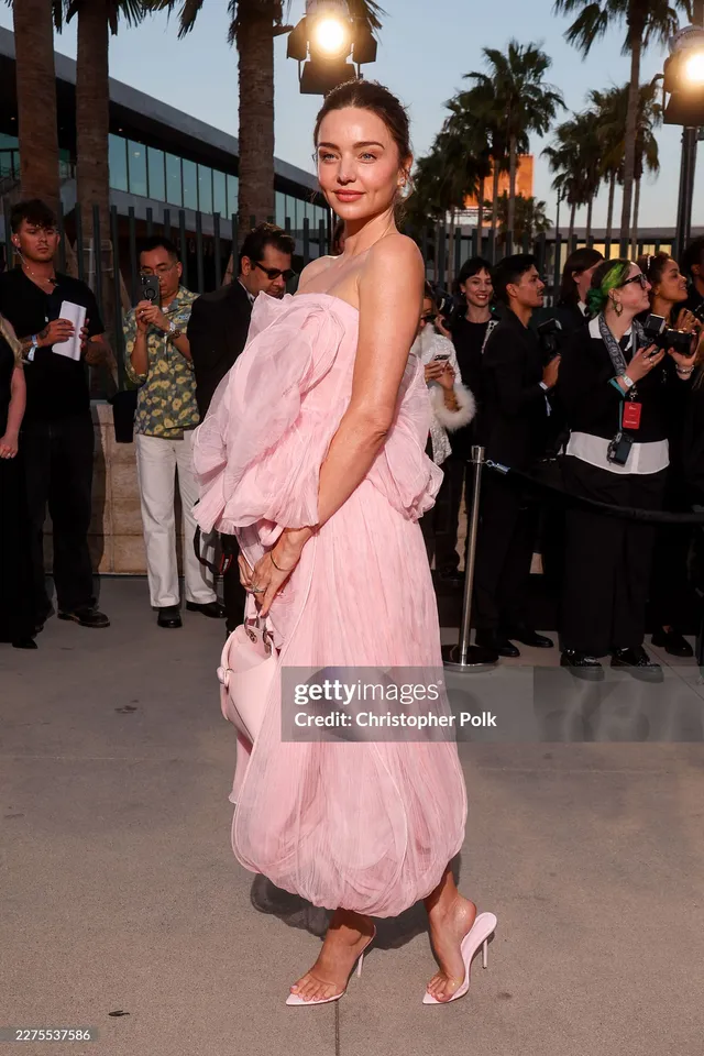Miranda Kerr a pink outfit and heels on a red carpet.