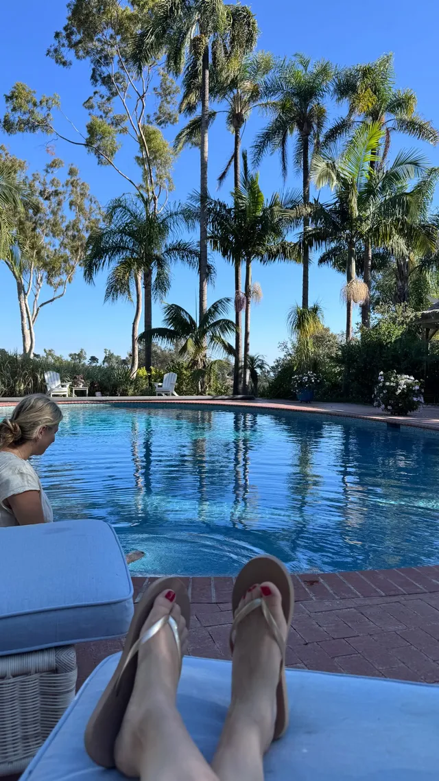 Kaley Cuoco wearing flip-flops beside a swimming pool.