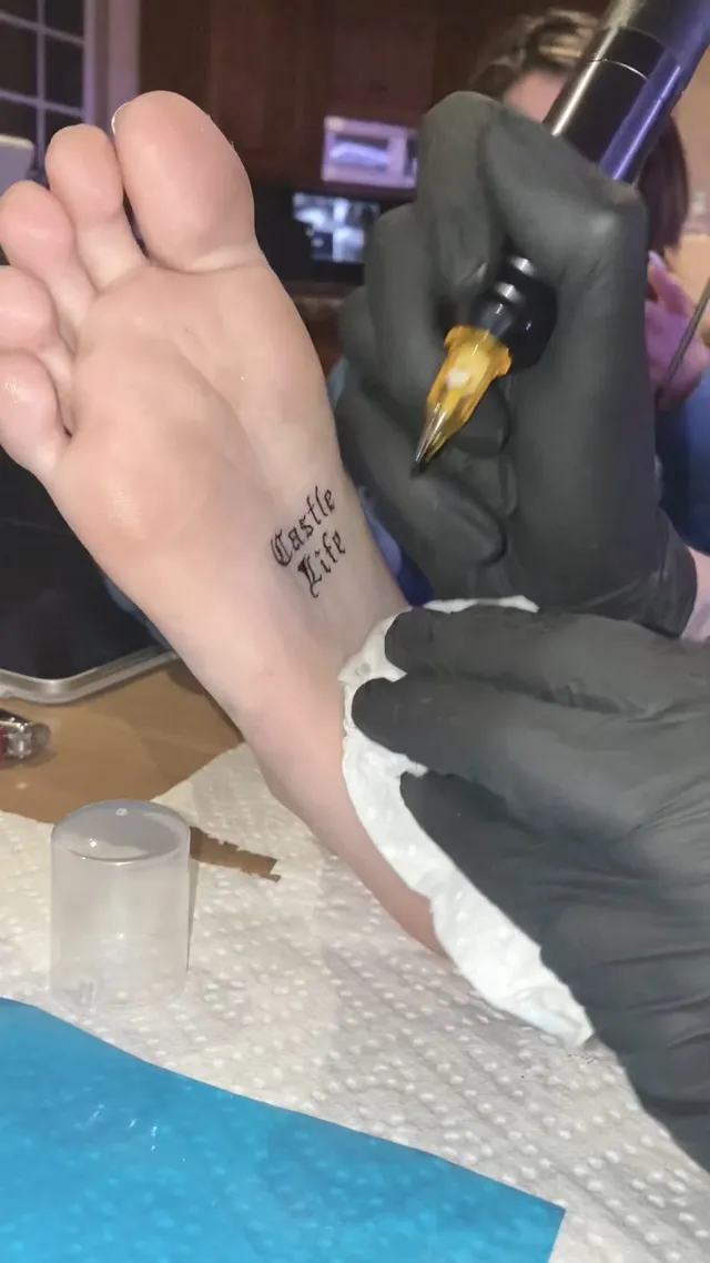 Madison Beer: close view of a bare sole during a tattoo session.