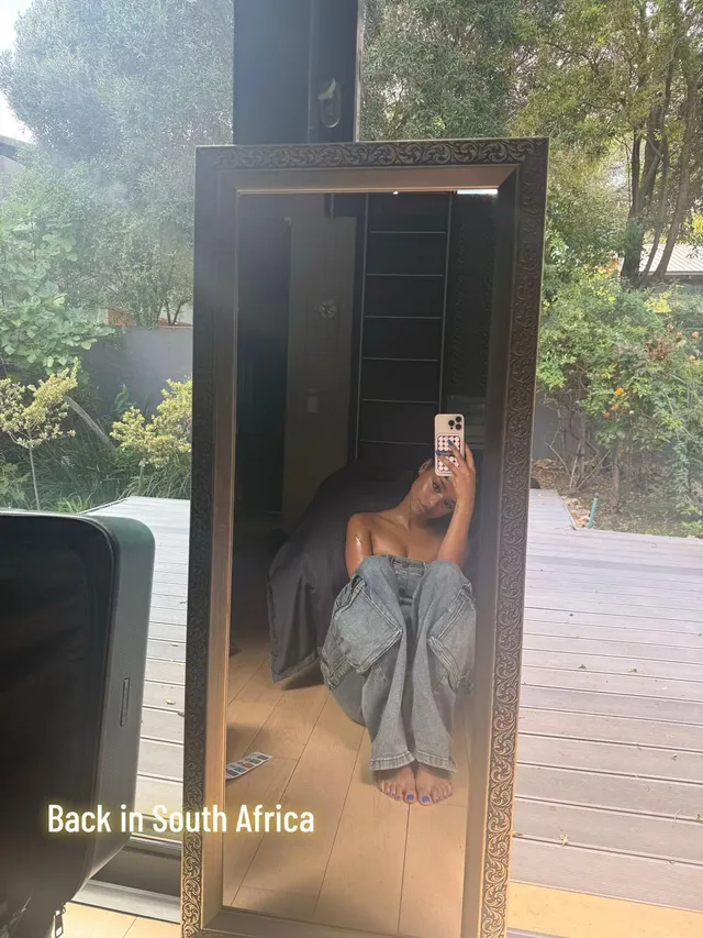 Tyla taking a barefoot mirror photograph while seated in a sauna.