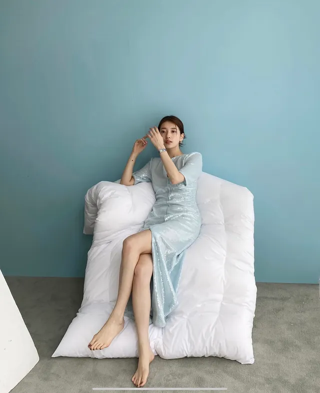 Bae Suzy sitting barefoot in a pale blue dress.
