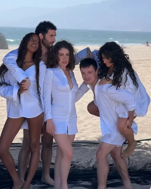 Odessa A'zion posing barefoot on a beach with cast members.