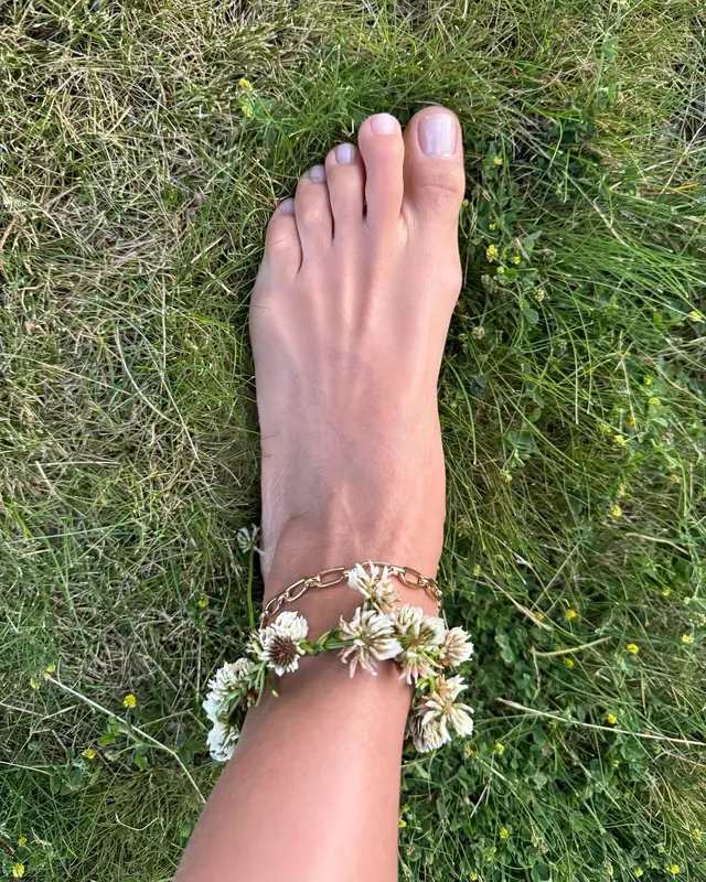 Irina Shayk a bare foot with a flower ankle bracelet on grass.