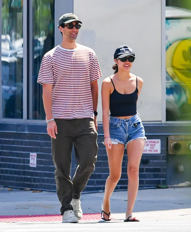 Olivia Rodrigo walking beside a companion outdoors.