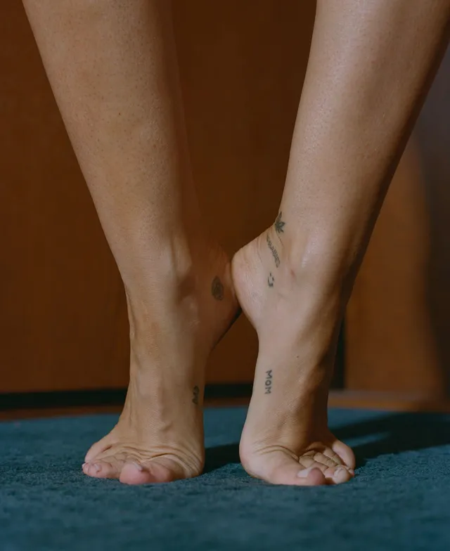 Miley Cyrus standing barefoot on a blue rug.