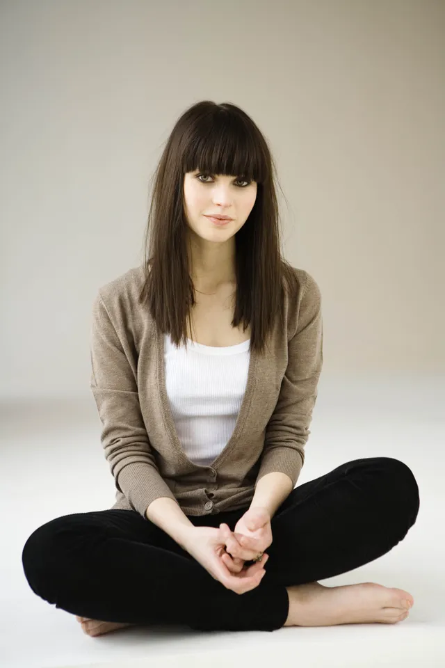 Felicity Jones sitting cross legged in a studio portrait.