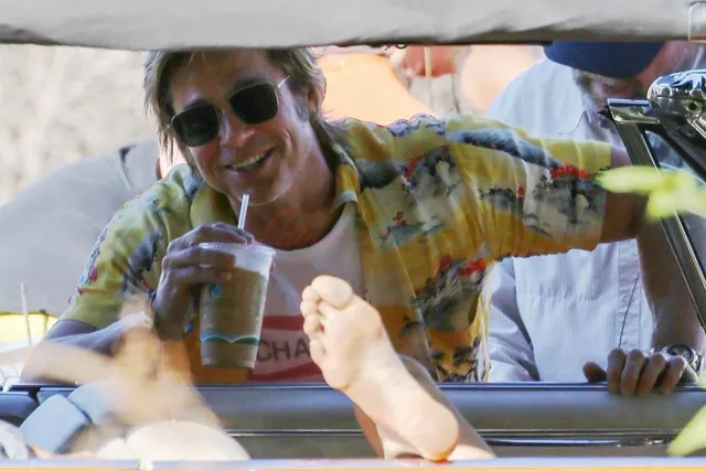 Margaret Qualley a car screen scene with bare feet raised beside another character.