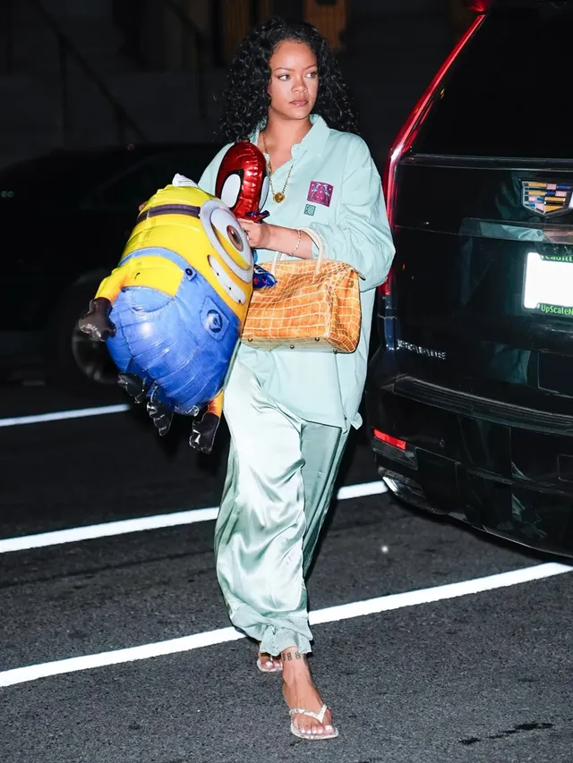 Rihanna walking at night in a pale green outfit and clear heels.