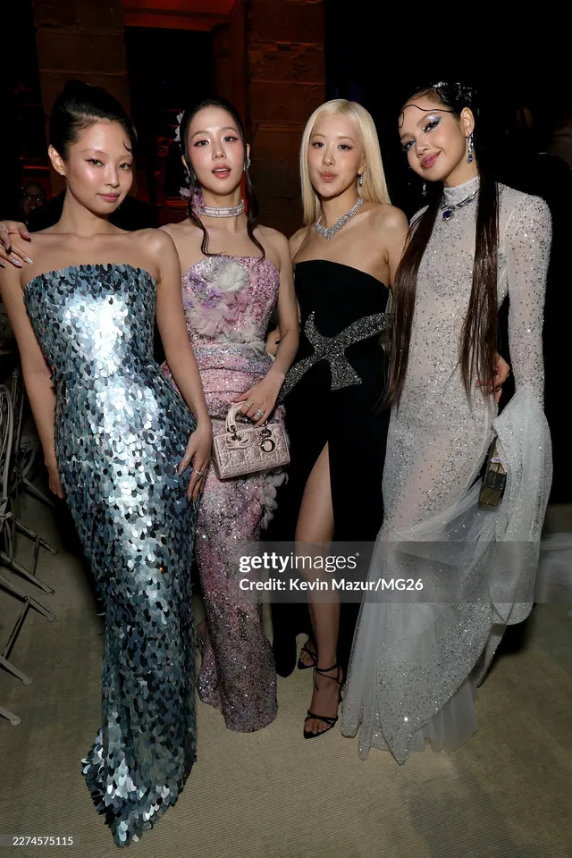 Rosé standing with a group of guests in a black gown and heeled sandals.