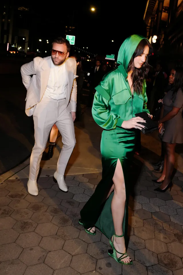 Grace Van Patten walking outdoors in a green dress and matching heels.