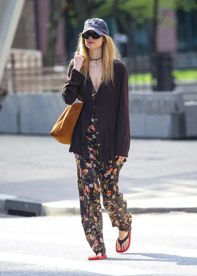 Jennifer Lawrence walking outside in a flowered outfit and flat sandals.