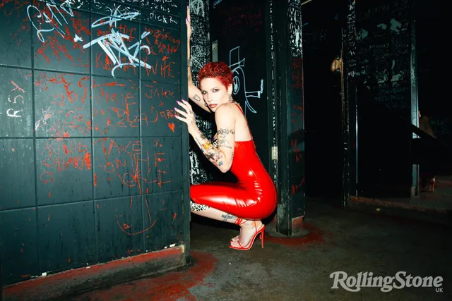 Halsey a red outfit and heels in a crouched portrait.