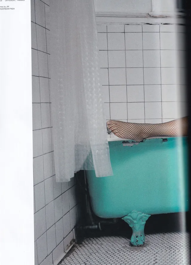 Naomi Scott a close screen detail of a foot in mesh stockings beside a bathtub.
