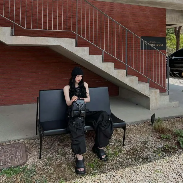 Han So-hee sitting outside in a black outfit and sandals.