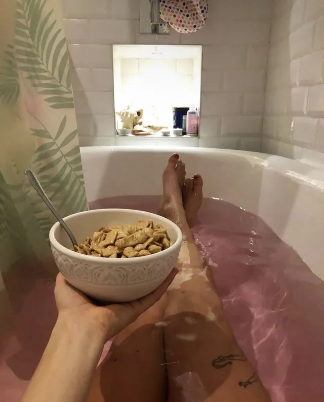 Ella Purnell relaxing in a bath with a bowl resting on her knees.