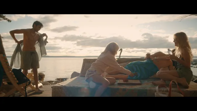 Emily Alyn Lind sitting with a group on a beach blanket in a screen capture.