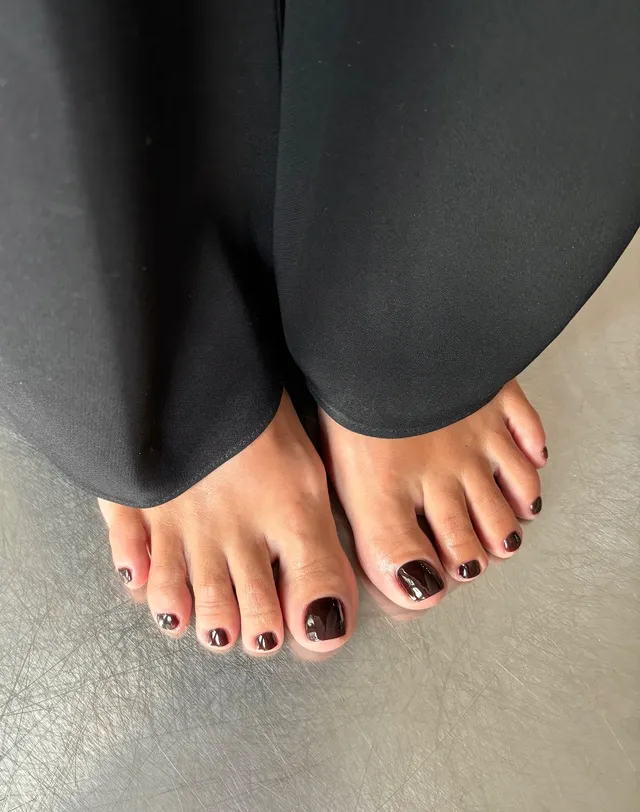 Lily Allen showing a dark pedicure beneath trousers.