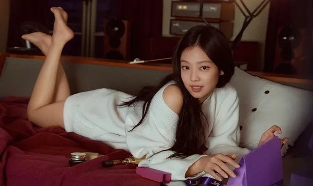 Jennie Kim lying on a bed with her bare feet raised during a campaign photograph.