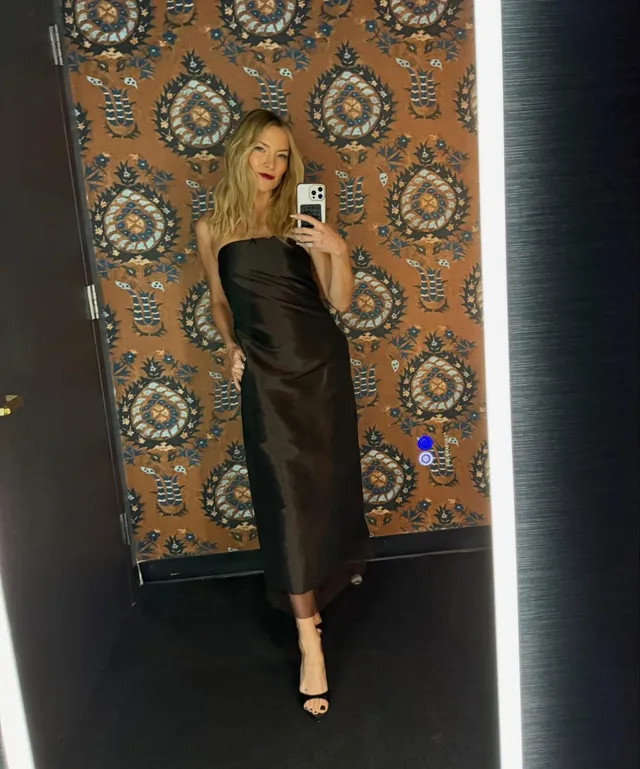 Kate Hudson taking a mirror photograph in a black evening dress.