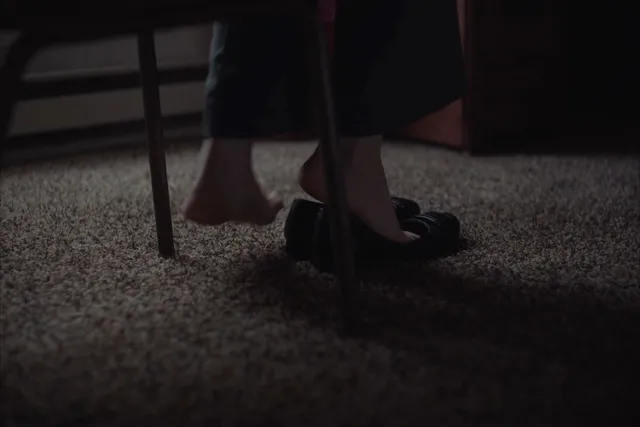 Daisy Ridley wearing pumps beside a chair in a screen scene.