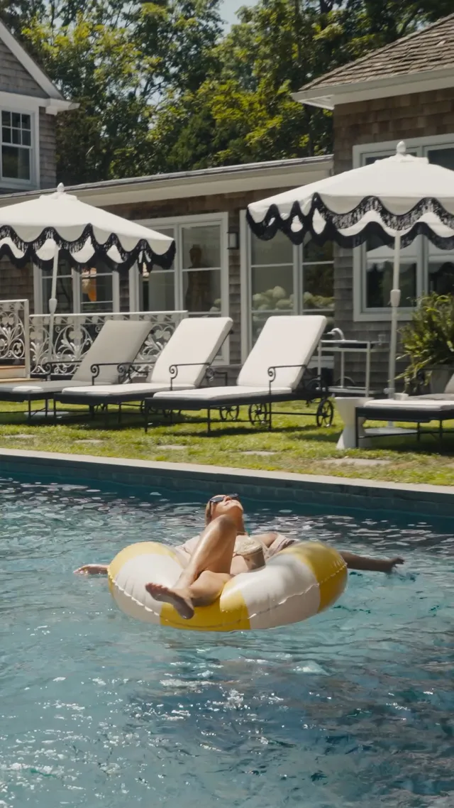 Bailee Madison reclining barefoot on a swimming pool float.