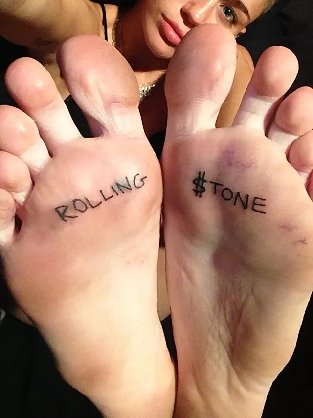 Miley Cyrus showing bare soles with handwritten words.