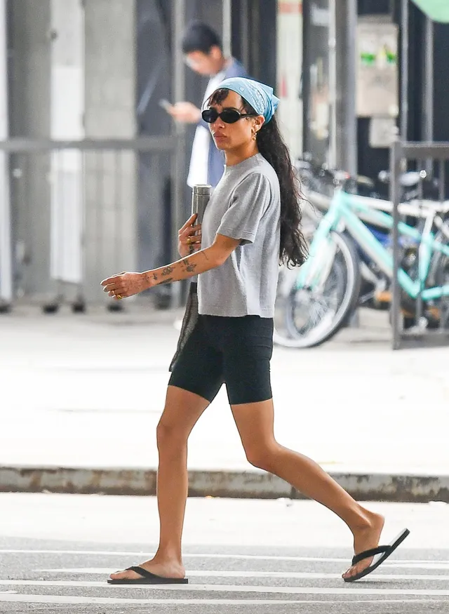 Zoë Kravitz walking outside in shorts and flat sandals.