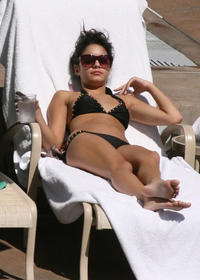 Vanessa Hudgens reclining on a lounger with bare soles visible.