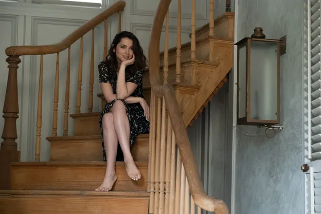 Ana de Armas sitting on wooden stairs.