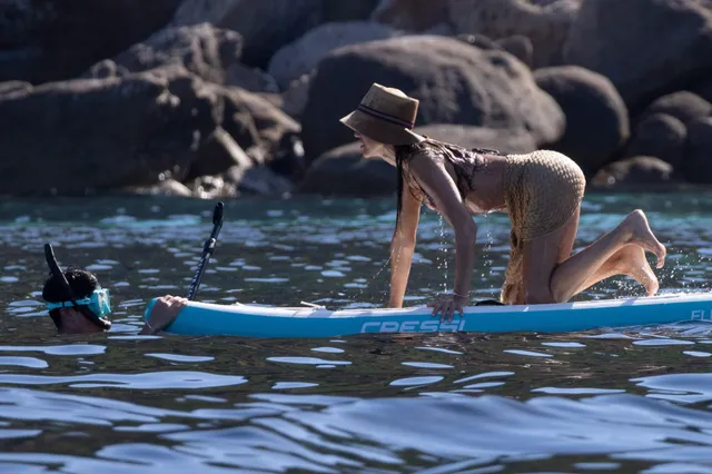Jessica Alba kneeling barefoot on a paddleboard.