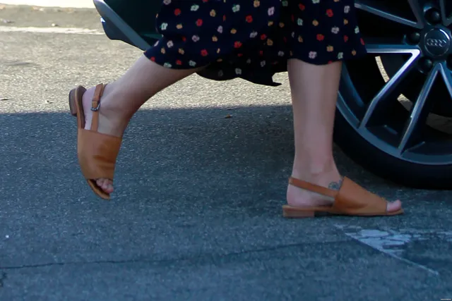 Melissa Benoist walking in a patterned dress and flat sandals.