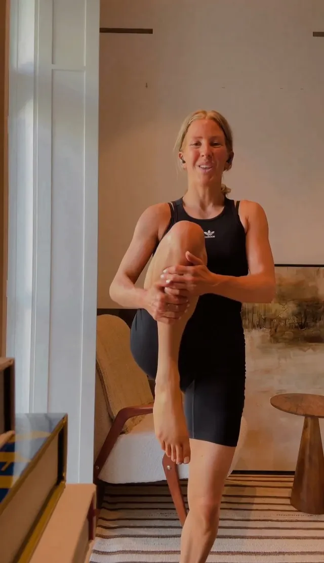Ellie Goulding holding a bare leg during an exercise stretch.