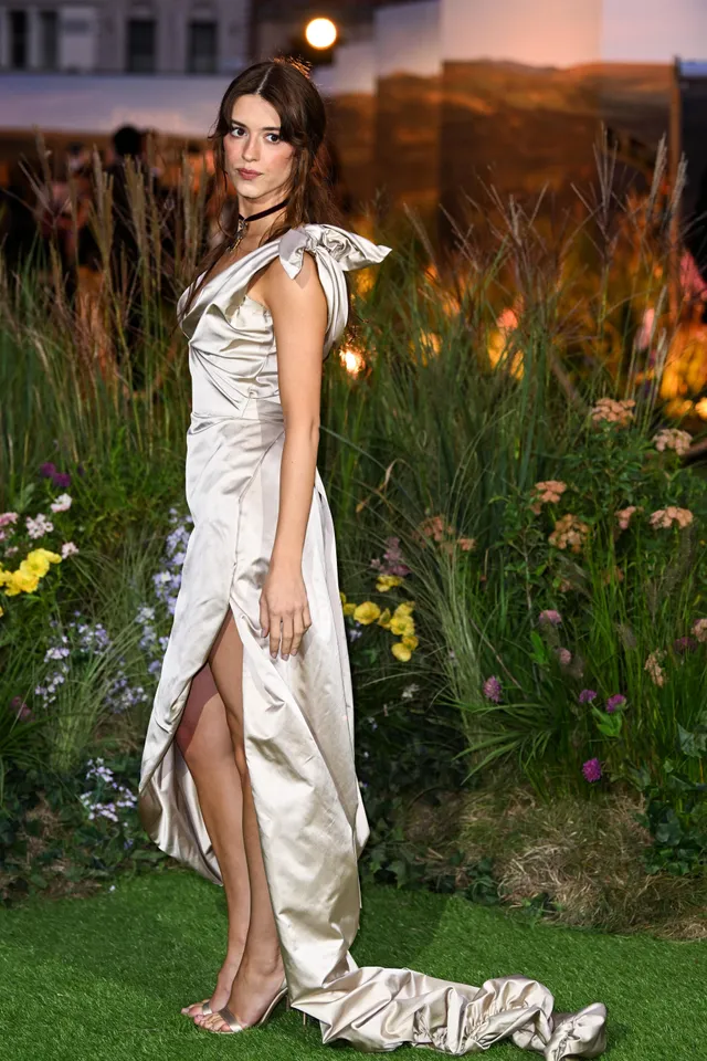 Daisy Edgar-Jones standing on a green carpet in a silver gown.
