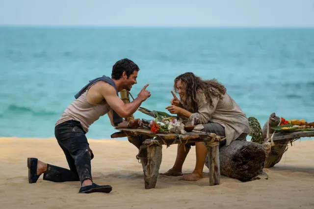 Rachel McAdams sitting at a beach table beside another person.