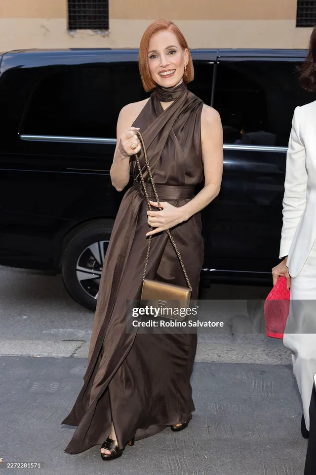 Jessica Chastain stepping from a vehicle in a brown gown.