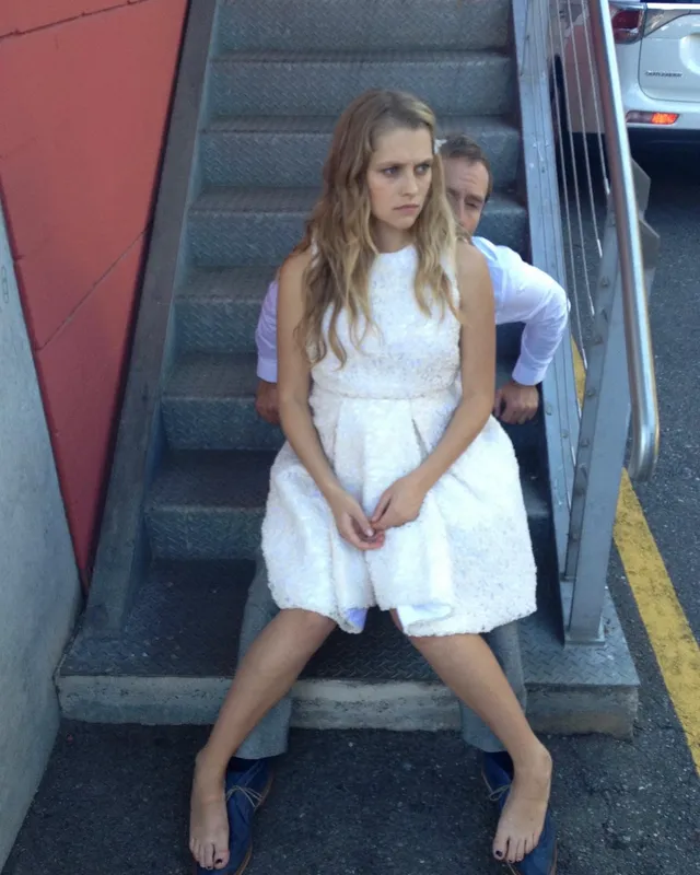 Teresa Palmer standing by a trailer in a short white dress.