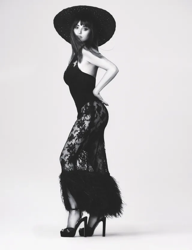 Penélope Cruz posing in a black dress and platform heels for a monochrome portrait.