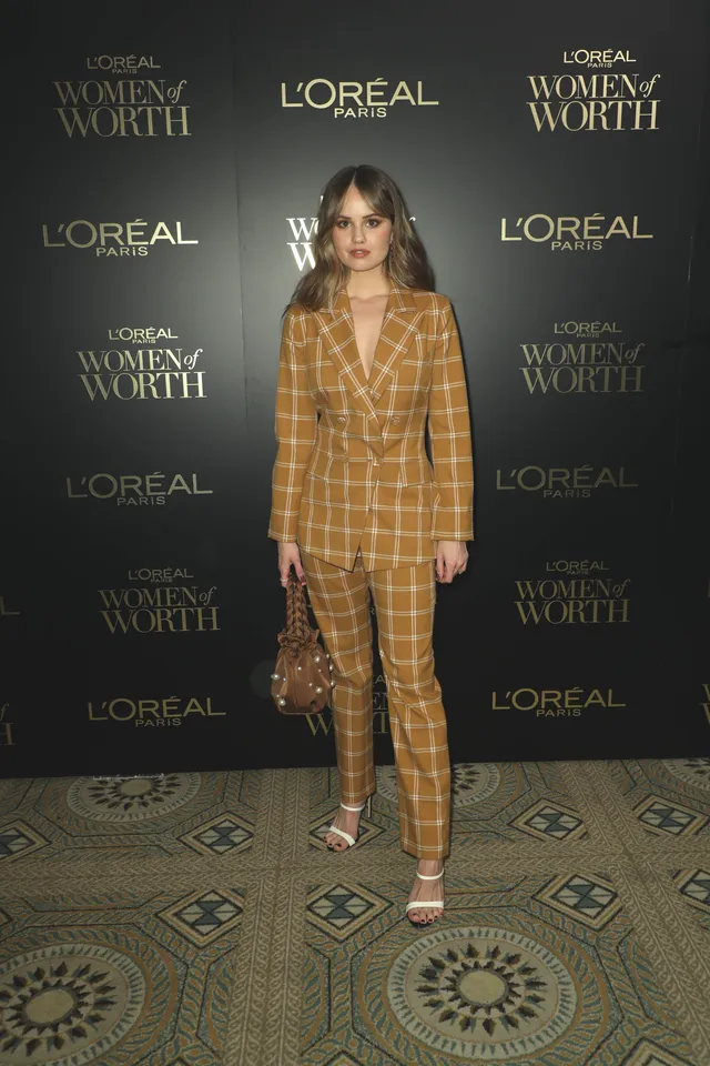 Debby Ryan wearing a checked suit and pale heels at an event.