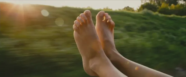 Sienna Miller resting bare feet beside an outdoor landscape.