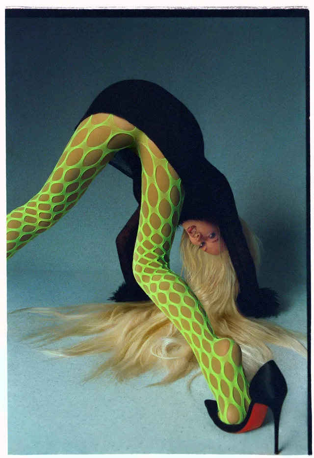 Christina Aguilera posing in patterned tights and black stilettos.
