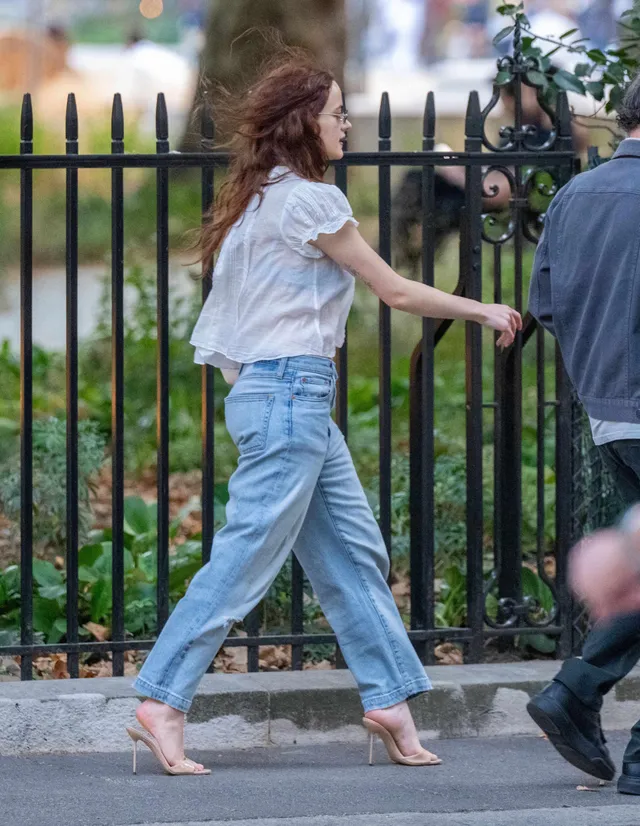Joey King walking outdoors in jeans and clear heeled sandals.