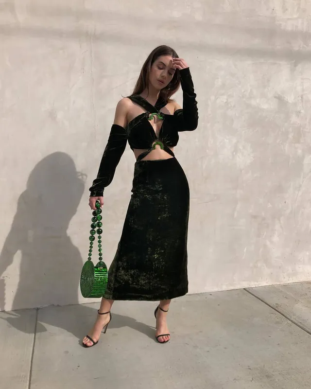 Adelaide Kane posing in sunlight in a dark outfit.