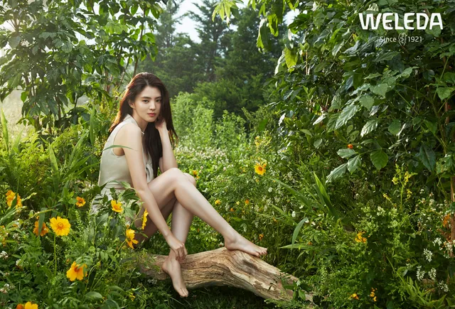 Han So-hee sitting barefoot among plants.