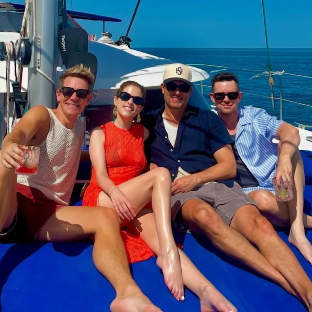 Anna Kendrick sitting barefoot with friends aboard a boat.