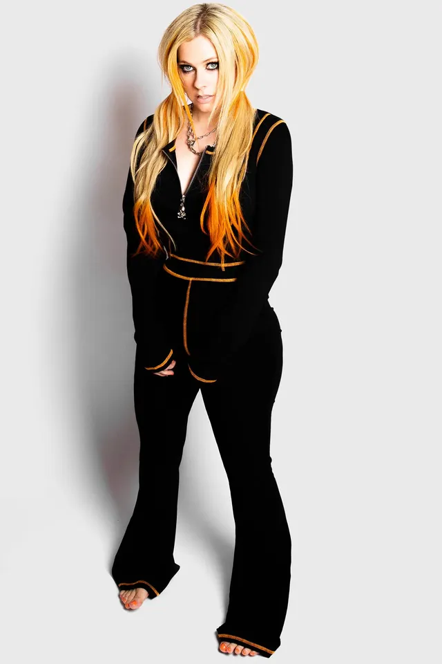 Avril Lavigne standing barefoot in a black outfit.